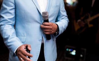 Man in blue suit holds a microphone