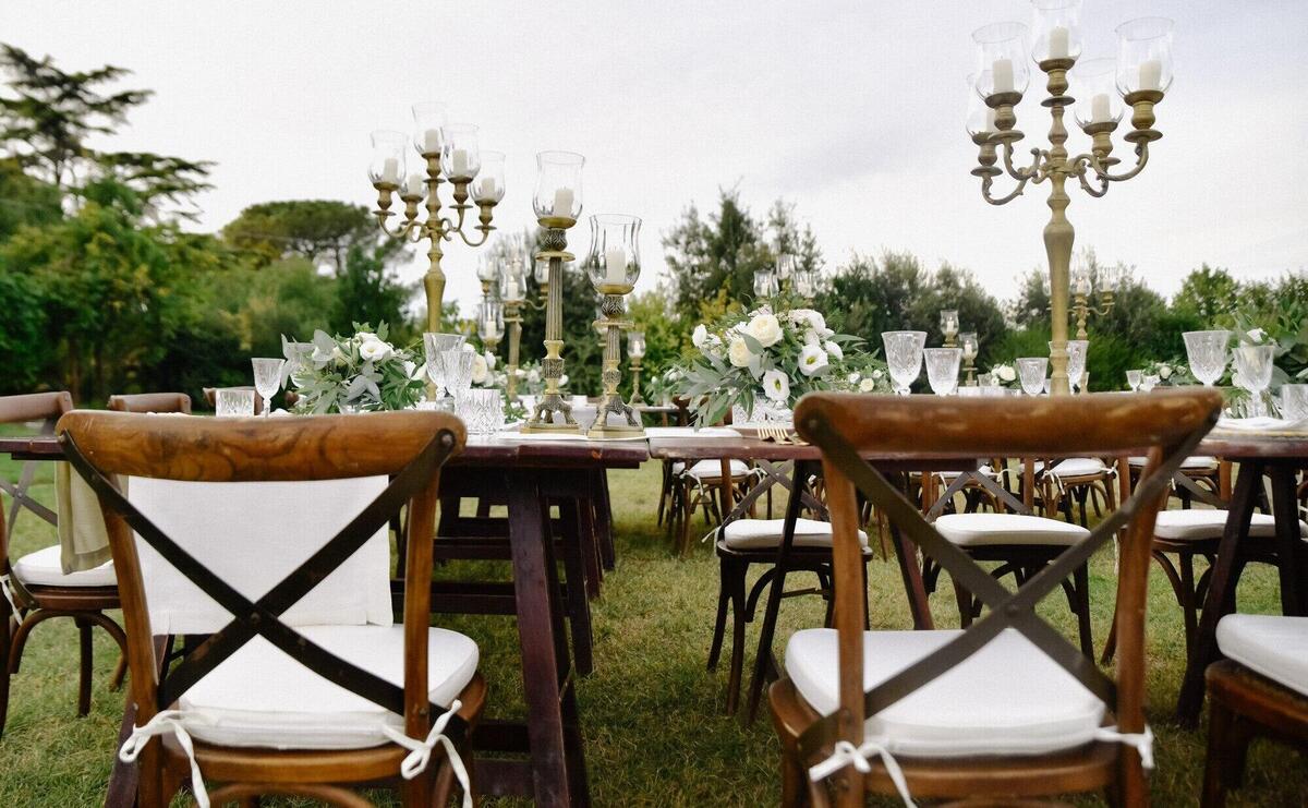 Decorated with floral compositions wedding celebration table with brown chiavari chairs guests seats outdoors in the gardens