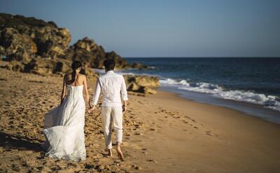 Bride and the groom walking at the sandy beach