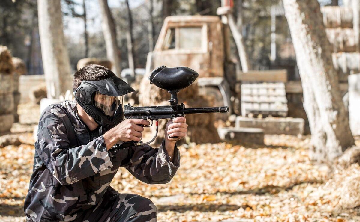 A man with a gun playing paintball.