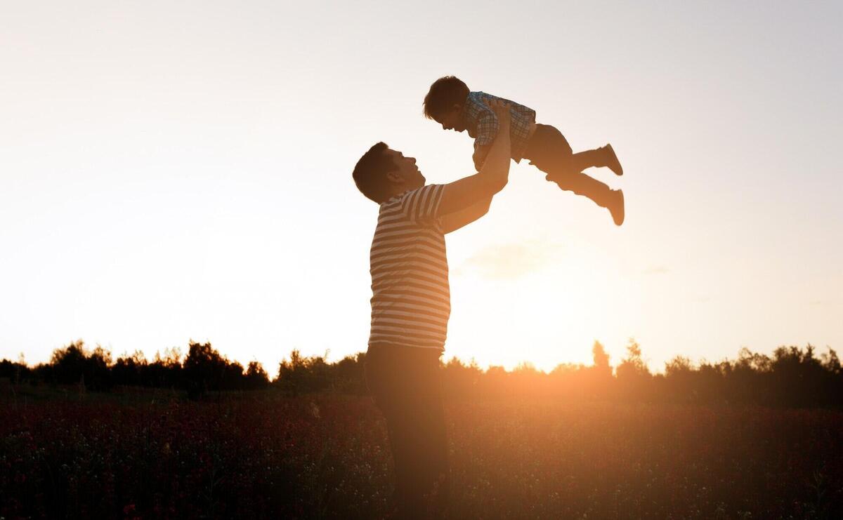 Father and son playing in the park at the sunset time. Happy family having fun outdoor