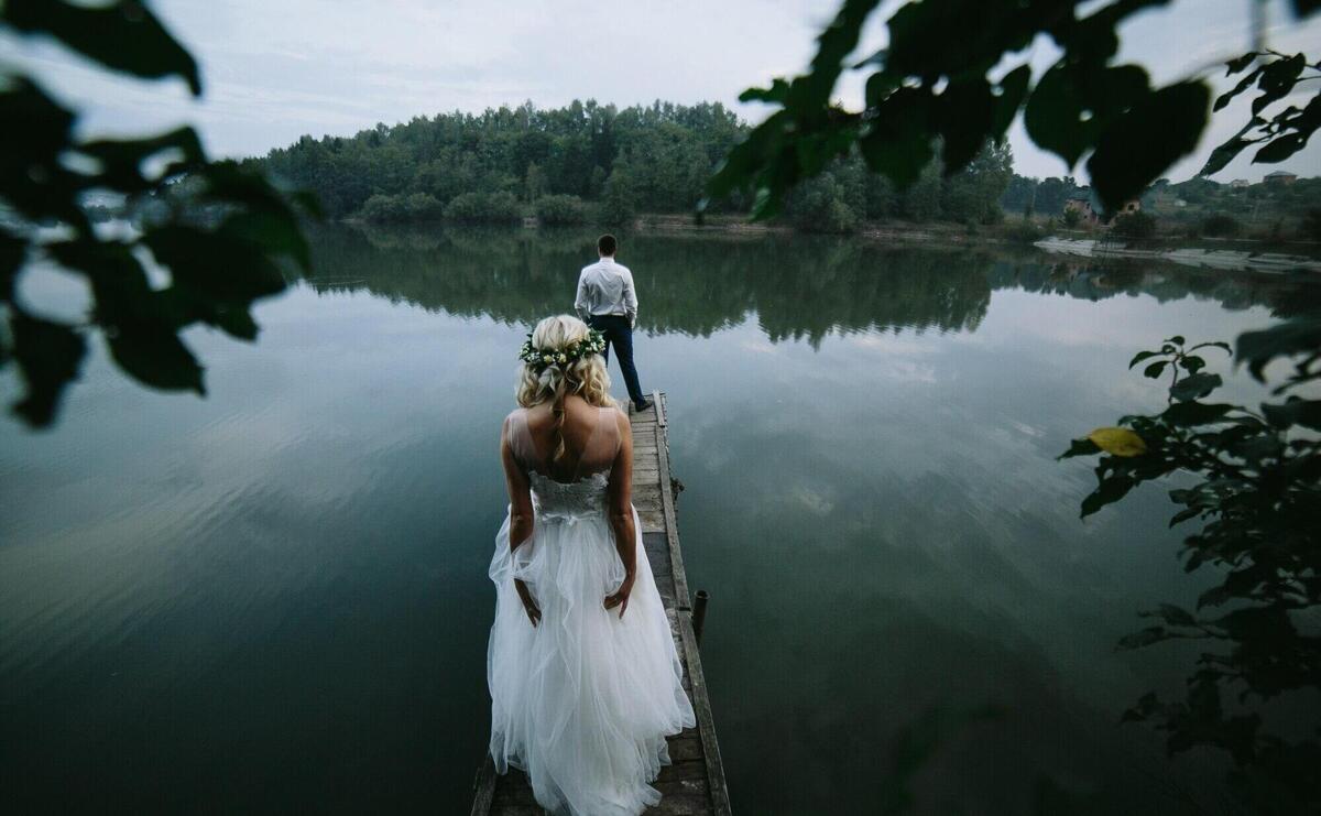 Bride with her husband in front looking at a lake