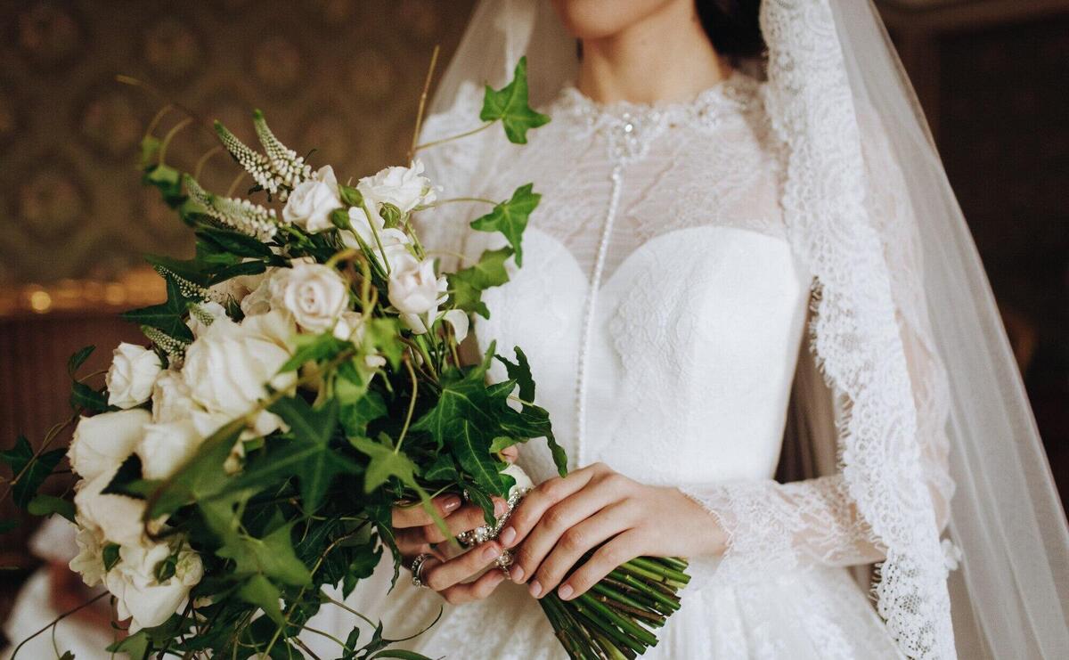 Bride holds wedding bouquet of white flowers in her hand