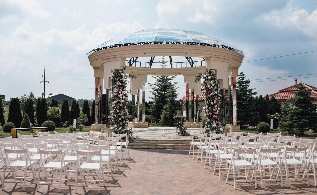 View of guest seats and ceremonial weddding archway on the sunny say, chiavari chairs, decorated territory