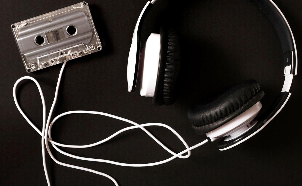 Headphone connected to transparent cassette on black background