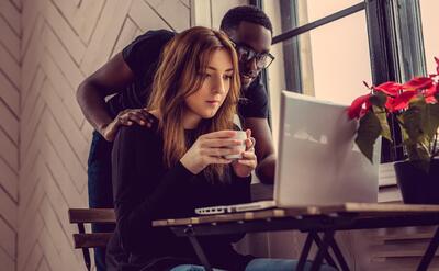 African american male and caucasian female using laptop at the table.