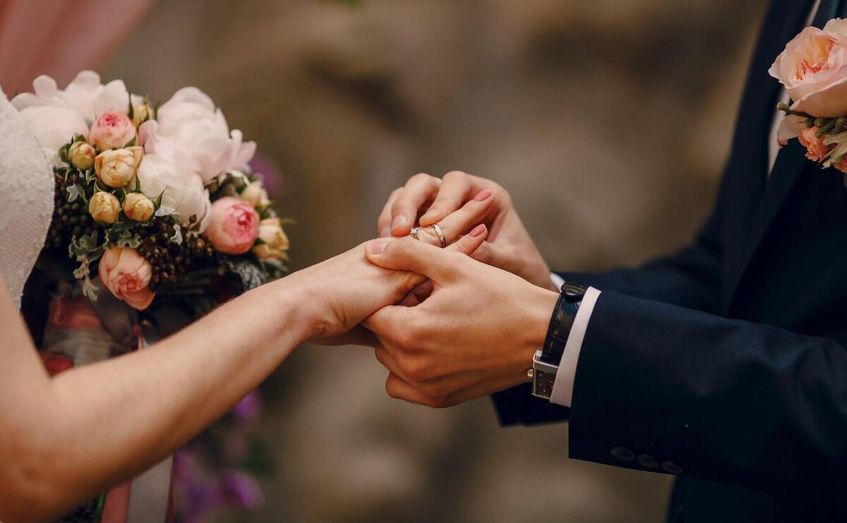 Groom putting ring on bride's finger