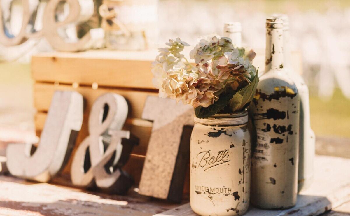 White old bottles with beige flowers stand before wooden 