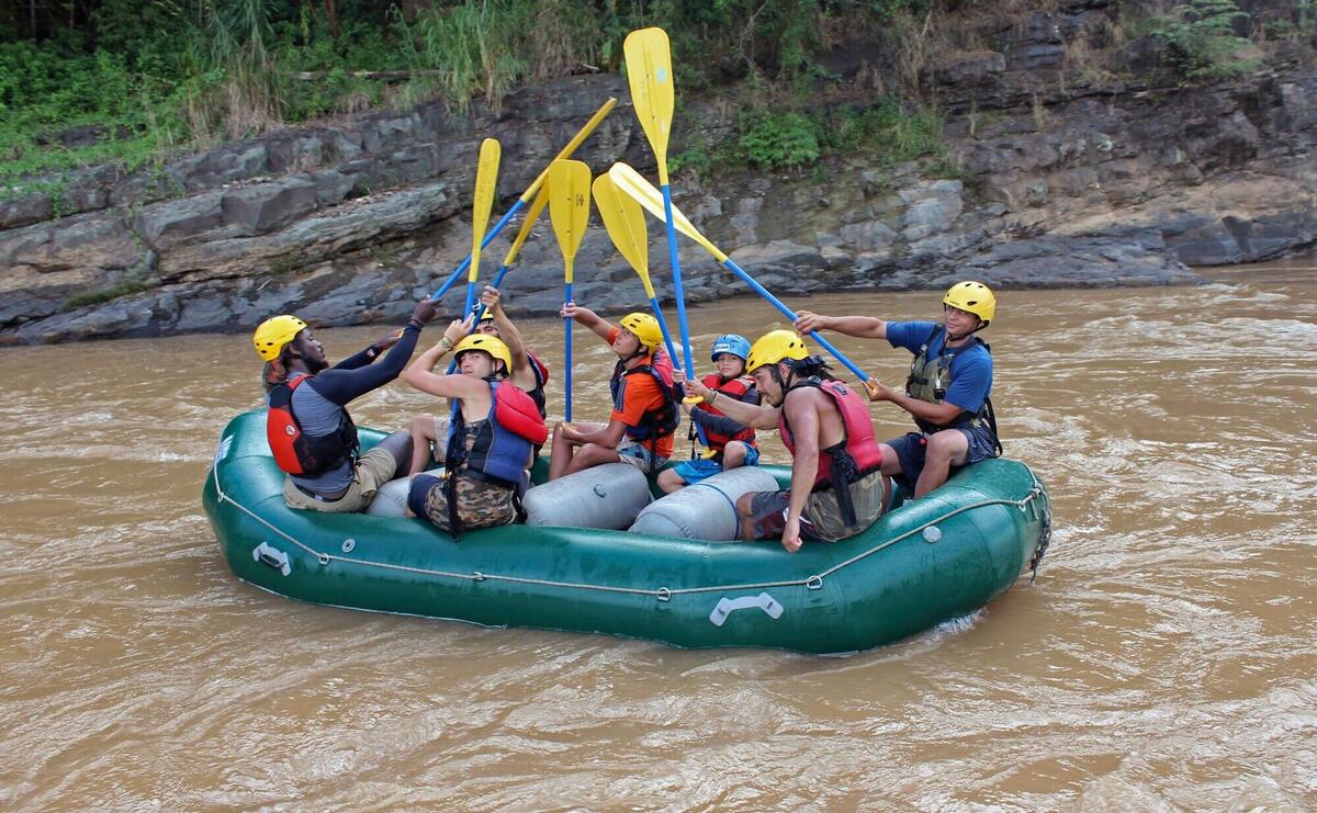 a group of people riding on the back of a raft down a river