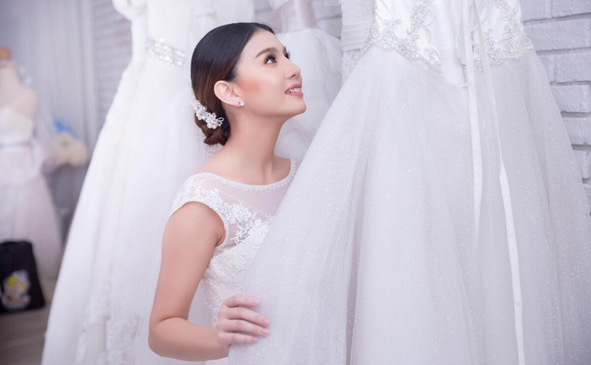 Asian young woman bride trying on wedding dress at modern wedding