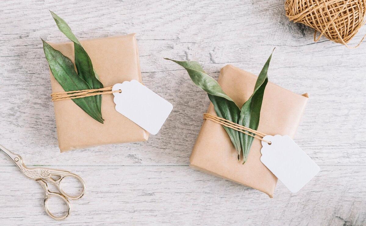 Scissor and wrapped presents with tag and leaves on wooden background